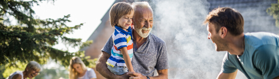 Grandpa carrying grandson during a family picnic