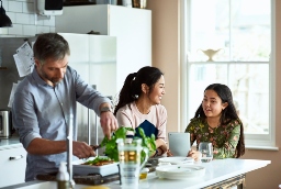Dad preparing food in the kitchen, while the children are talking getting ready for dinner